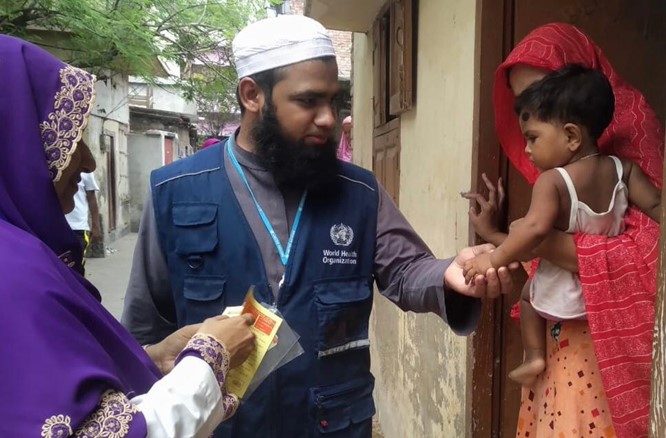 Dr. Faisal checking the vaccination status of children while doing RCA and giving health education to the mother. Photo Credit: WHO Bangladesh