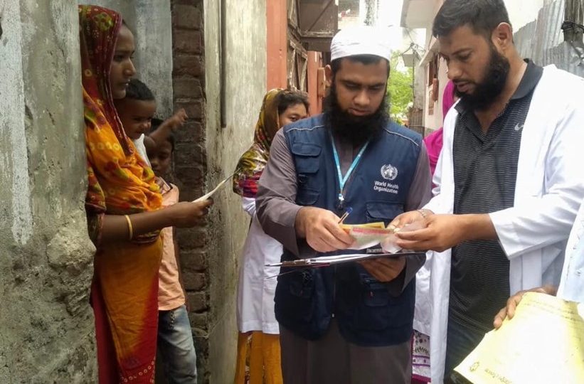 Dr. Faisal searching for zero doses and under-immunized children by comparing the immunization card in a high-risk urban dense area. Photo Credit: WHO Bangladesh